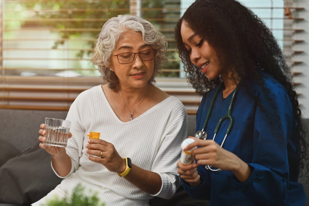 iStock-1735417950-min-min young nurse sits helping older woman with her medications