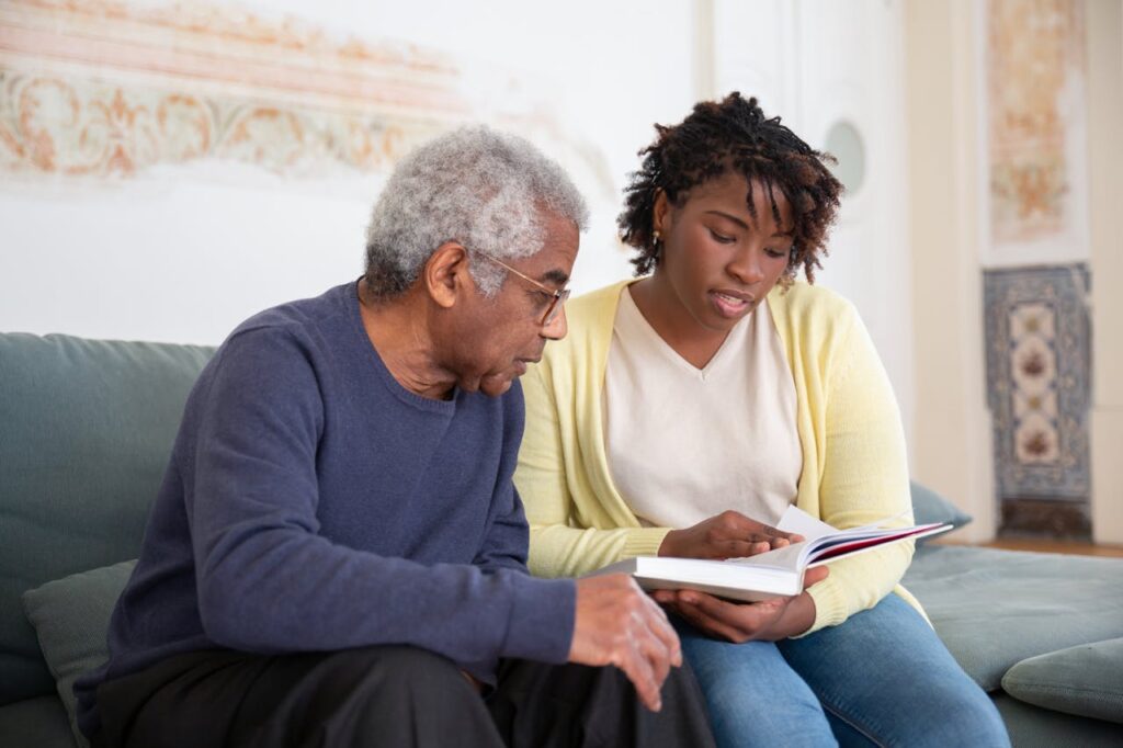 Young caregiver reading with an elderly man in his home