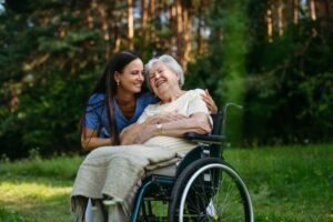 Caregiver comforts an elderly woman outdoors, highlighting the need for 24-hour care support